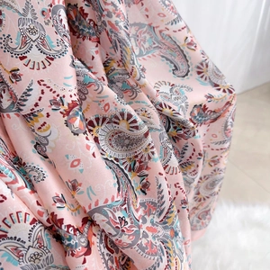 Detail view of pink paisley pattern fabric with silky texture and vibrant colors