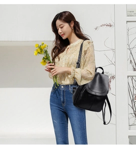 Chic black faux leather anti-theft backpack for women shown in a street style look