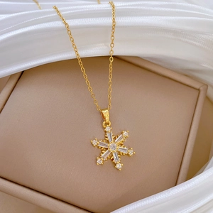 Makroaufnahme einer goldenen Schneeflocke-Halskette mit funkelnden Kristallen