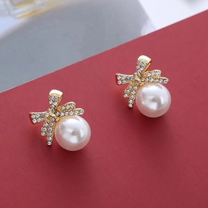 Vue macro des boucles d'oreilles papillon dorées avec zircons et perles blanches