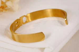 Detailed macro view of the gold cutout LOVE letter bracelet on soft fabric background
