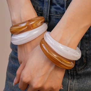 Close-up of resin cuff bracelets with marble pattern on a denim fabric background