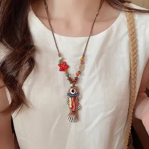 Handmade ceramic fish necklace with starfish and colorful wooden beads on linen