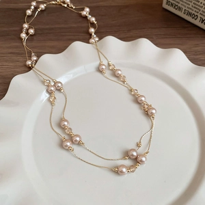 Détail d'un collier de perles multicouche doré champagne sur une assiette en céramique