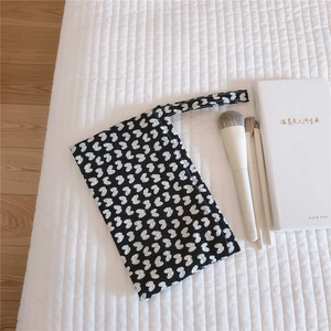 Detailed macro view of black fabric mini pouch with white bow patterns and texture