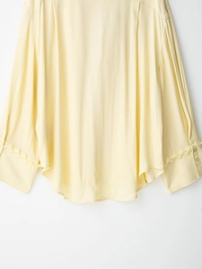 Detail of pale yellow chiffon blouse showing crepe texture and lace cuffs with gold buttons