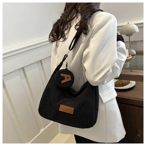 Detail of black corduroy shoulder bag with letter A charm and brown leather patch decoration