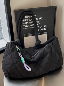 Black quilted tote bag with colorful charm on a metal desk in a modern studio