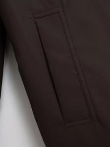 Detailansicht der dunkelbraunen Kapuzenjacke mit Fokus auf Stoff und Taschendetails