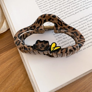 Detailed view of leopard print hair claw clip with black bear and yellow heart motif