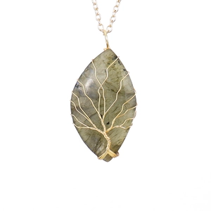 Macro shot of leaf-shaped labradorite pendant with gold tree of life wire wrapping