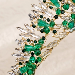 Macro detail of gold bridal crown with sparkling crystals and emerald green gemstones