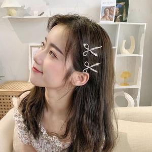 Close-up of silver rhinestone bow and scissors hair clips on a female model