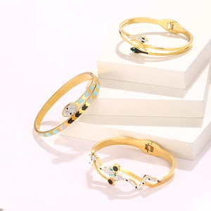 Golden snake-shaped bangle set with sparkling rhinestones and crystal accents on white pedestals