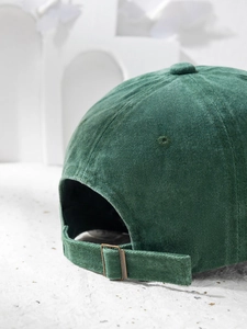 Detail of adjustable metal buckle and corduroy texture on dark green baseball cap