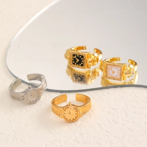 Detail shot of vintage watch-style adjustable rings in gold and silver on a mirror