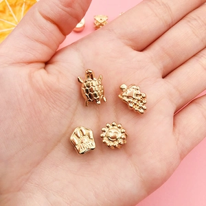 Detailed close-up of KC gold DIY charms including turtle, grape, sun, and MOM paw print