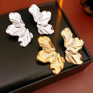Detailed view of leaf-shaped metal earrings in gold and silver on a display stand