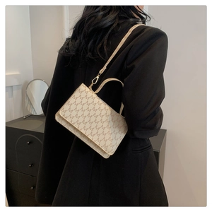 Detail of minimalist beige rectangular crossbody bag with M-pattern and gold hardware