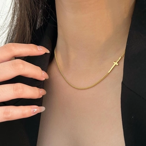 Close-up of minimalist 925 sterling silver golden cross necklace on model in black suit