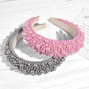 Pink and grey padded headbands with elegant large pearls on a white wooden background