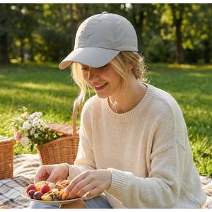 Detail einer Frau mit einer hellgrauen, atmungsaktiven Baseballkappe bei einem Picknick
