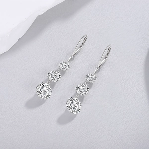 Macro shot of silver drop earrings featuring a gradient of three round cut sparkling stones