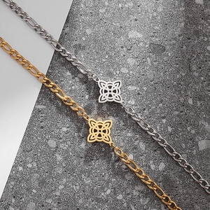 Detail of Figaro chain bracelets in gold and silver with clover-shaped Celtic knot charms