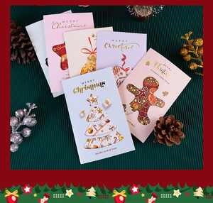 Detail of laser-cut Christmas cards with gold foil greetings and festive pine cone decor