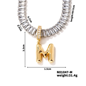 Detailed view of golden bubble M letter pendant with clear cubic zirconia necklace chain
