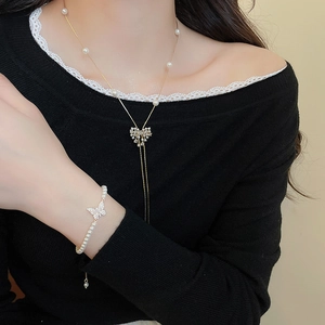 Macro detail of 18k gold plated butterfly necklace and bracelet set with pearls