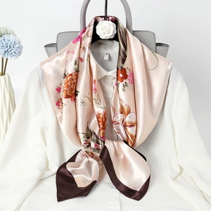 Detail of champagne pink floral silk square scarf tied elegantly on a white blouse