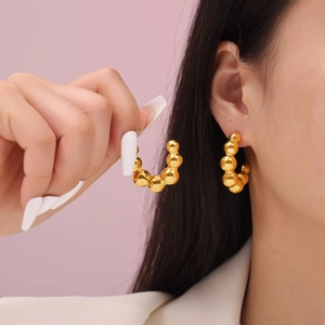 Minimalist gold-plated titanium steel beaded hoop earrings worn by a model