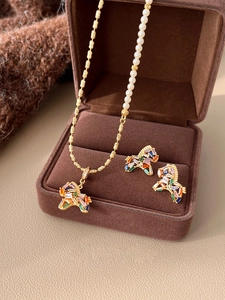 Detail of gold-plated horse pendant and pearl earrings in a luxury jewelry gift box