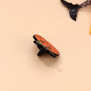 Side view of Halloween pumpkin enamel pin showing metal needle structure and orange finish