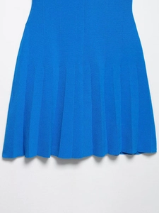 Detailopname van de geplooide zoom van deze felblauwe gebreide overhemdjurk