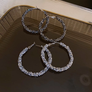 Detailed view of silver hoop earrings featuring sparkling rhinestones on a textured tray