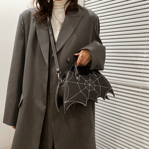 Detail view of black PU bat-shaped handbag with white spiderweb stitching and metal spider
