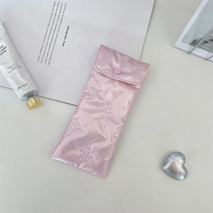 Close-up of pink satin bow quilted glasses pouch featuring a heart-shaped snap button