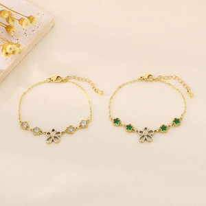 Detailed shot of gold flower bracelets with white and green zircon on fabric