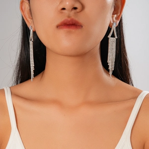 Gros plan de boucles d'oreilles géométriques à glands diamantés portées par un mannequin