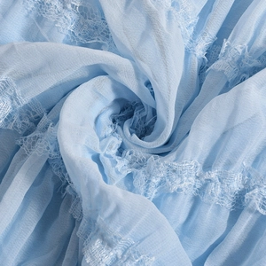 Detailed view of light blue dress fabric featuring delicate lace trim and soft pleats