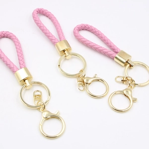 Pink braided leather keychain with golden alloy ring and lobster clasp on white background