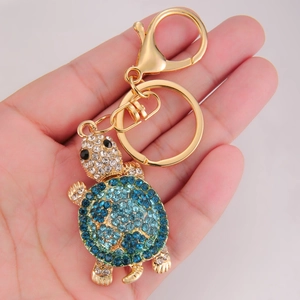 Handheld turtle keychain with vibrant blue and green rhinestones on a gold metal frame
