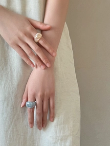 Detail of two oval resin rings with marble texture in beige and light blue on a model