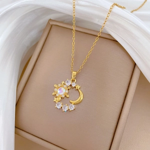 Macro shot of gold moon and star pendant with opal stone on white silk background
