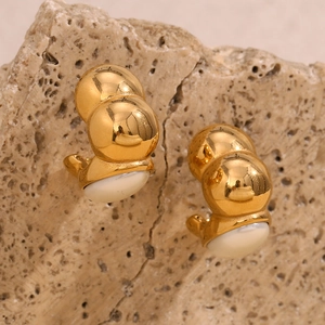 Vue macro de boucles d'oreilles en acier doré 18 carats avec émail blanc incrusté