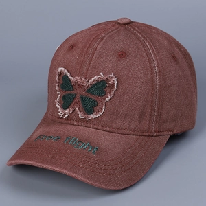 Detail of red vintage denim baseball cap featuring butterfly patch and Free flight embroidery