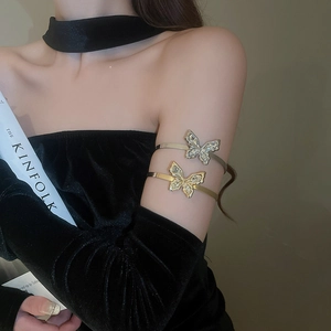 Close-up of sparkling crystal butterfly arm cuffs in gold and silver on a female arm