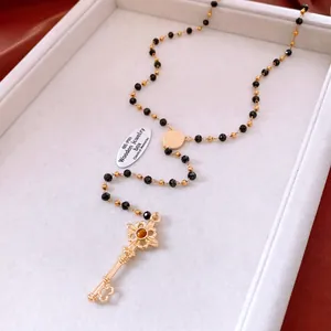 Détail du collier à pendentif clé vintage avec pierre ambre et chaîne de perles noires